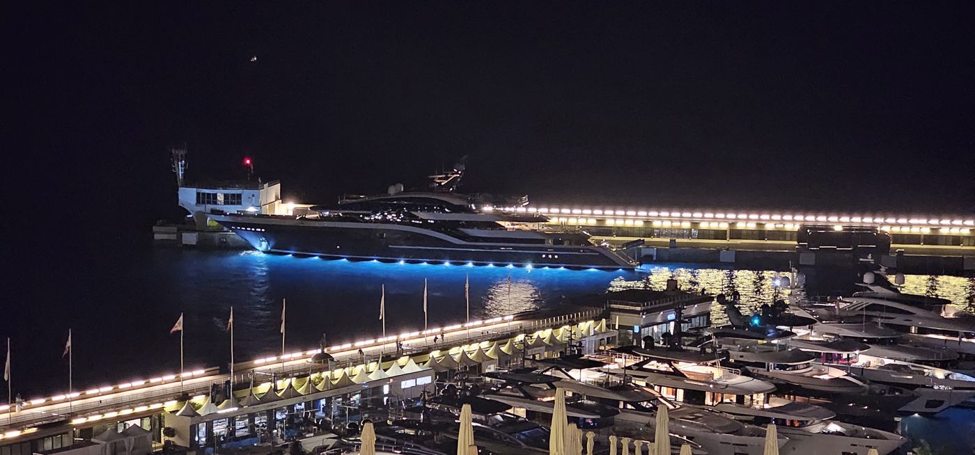 A superyacht lit up at night in Port Hercule