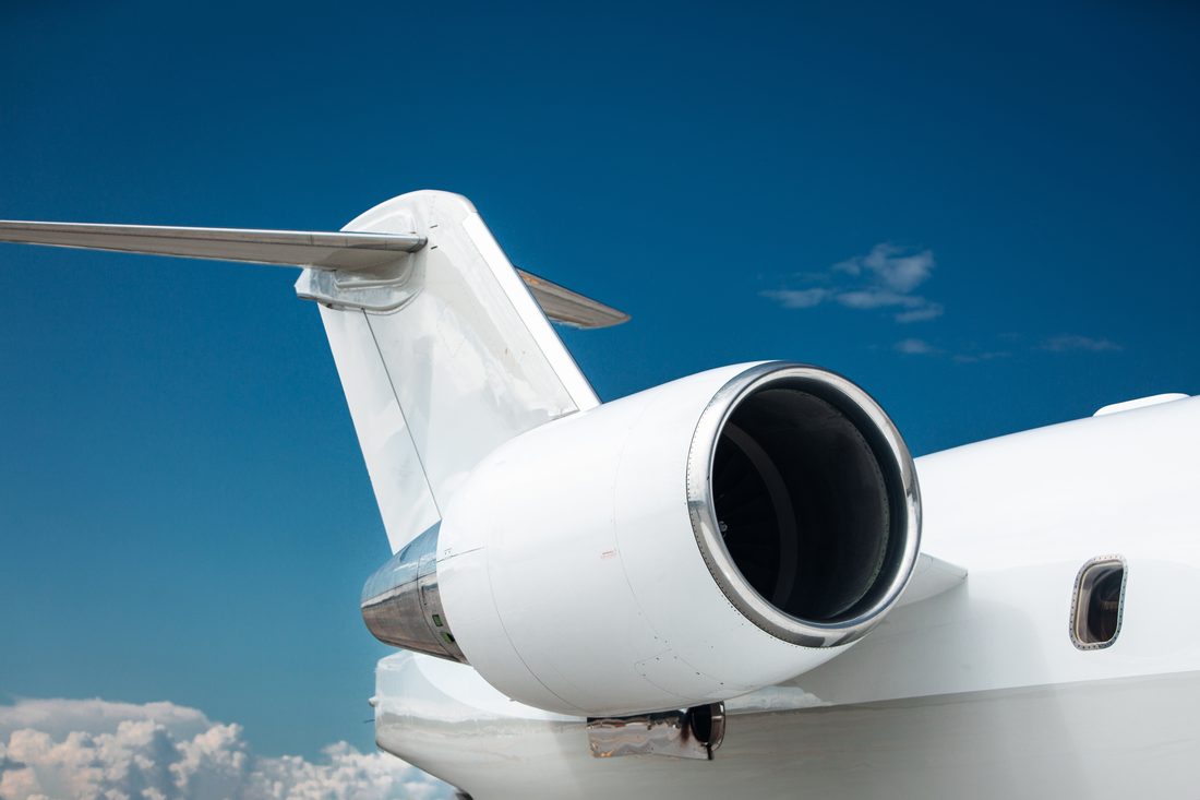 Private jet tail and engine against a blue sky